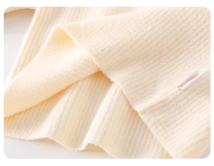 Close-up of soft off-white ribbed knit fabric detail for baby winter clothing set