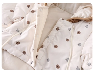 Close-up of white baby winter romper with pumpkin print, zipper pockets and hood details