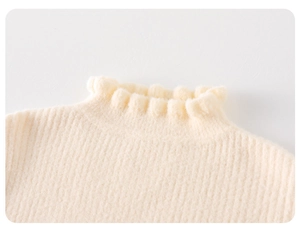 Detail of baby girl cream knit sweater showing ruffled high neck and ribbed texture