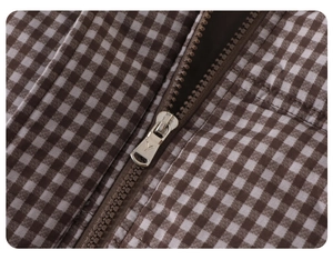 Macro shot of the durable silver metal zipper on the brown gingham puffer jacket fabric