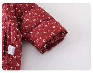Macro shot of red floral quilted jacket details with elastic cuffs and wash care label