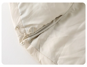 Close-up detail of adjustable drawstring hem on a beige padded winter jacket for babies