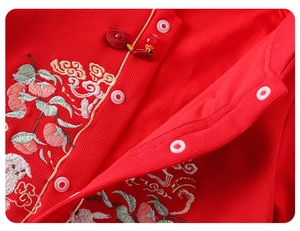 Detail eines roten Baby-Stramplers mit traditioneller Stickerei und Stoffstruktur