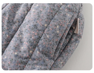 Detail view of thickened floral quilted fabric with soft blue pattern and woven label