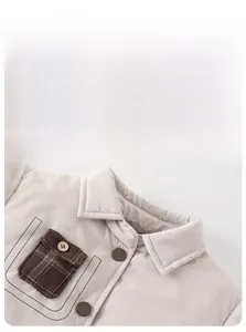 Détail d'une veste d'hiver pour bébé avec poche à carreaux et bouton en bois décoratif