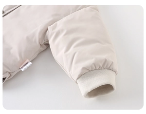 Gros plan détaillé d'une doudoune beige pour bébé avec poignets en tricot et étiquette
