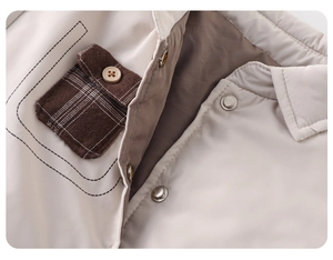 Gros plan d'une veste d'hiver beige avec poche à carreaux marron et boutons-pression argentés