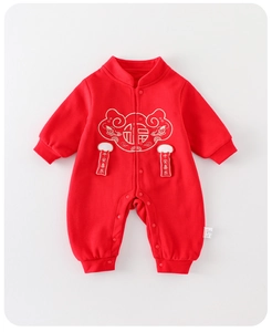 Détail d'une grenouillère rouge avec broderie Fu dorée et breloques Ping An Xi Le