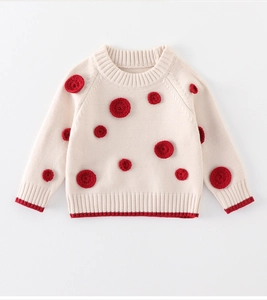Detail of baby knit sweater featuring 3D red crochet appliques and ribbed hem
