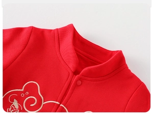 Détail de l'encolure d'un barboteuse bébé en coton rouge avec broderie blanche et boutons