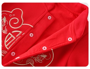 Détail macro du col d'un barboteuse bébé rouge avec boutons et broderie fine