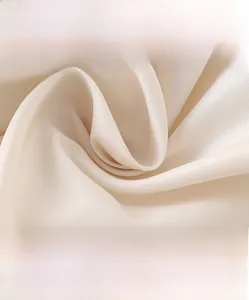 Macro detail of soft beige down jacket fabric with a smooth satin texture and fine weave
