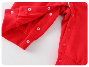 Detail of red ribbed baby romper featuring durable white snap closures and soft fabric