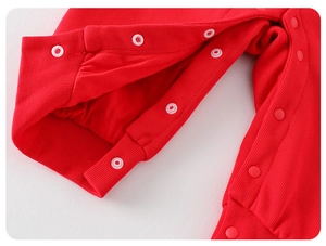 Détail de la barboteuse rouge pour bébé montrant les pressions et la texture du tricot