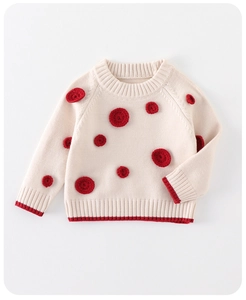 Detailed macro view of cream knitted baby sweater with red crochet dots and ribbed edges