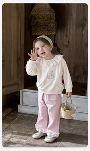 Detail of baby girl sweatshirt with floral ruffle collar and lace-trimmed pink trousers