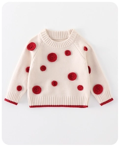 Detailed knit texture of a cream baby sweater featuring 3D red crochet polka dots