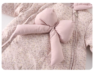 Close-up of pink floral baby romper featuring a large bow and warm textured fabric