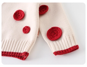 Close-up of cream knit sweater showing red crochet patches and ribbed stripe detailing