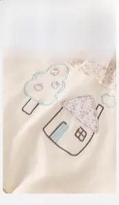 Close-up of baby girl sweatshirt with embroidered tree, house and floral ruffle collar