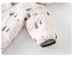 Detail of baby winter jumpsuit featuring quilted forest print with deer and star patterns