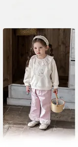 Detail of girls floral ruffle beige sweatshirt and pink trousers set for spring fashion