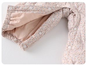 Detailed macro view of the snap button closure and floral print on baby romper