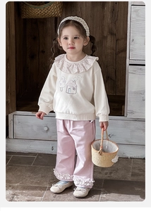 Detail of baby girl sweater with ruffle floral collar and house pattern embroidery