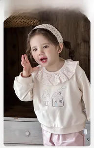 Detail of baby girl sweatshirt featuring floral ruffle collar and house embroidery