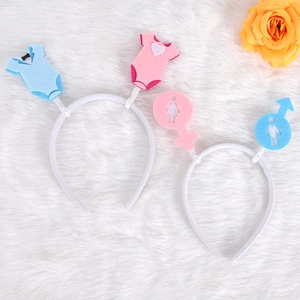 Gender reveal party headbands with pink and blue baby onesies on white plush background