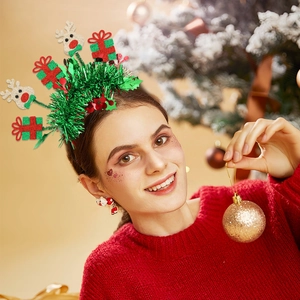 Detalle de diadema navideña con espumillón verde y adornos festivos de renos y regalos