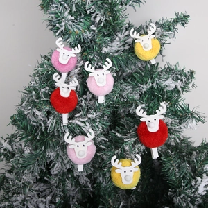 Weihnachts-Rentier-Holzklammern mit bunten Bommeln an verschneiten Tannenzweigen