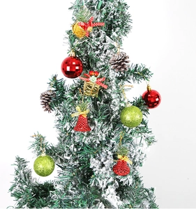 Détail de décorations de Noël incluant boules disco, cloches et pommes de pin sur branche