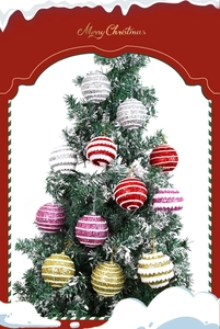 Detail of glittery striped Christmas tree baubles hanging on snowy branches