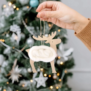 Pendentif renne de Noël en bois avec centre en laine suspendu sur un sapin