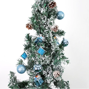 Gros plan d'ornements bleus et pommes de pin sur un sapin de Noël enneigé artificiel
