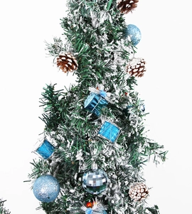 Détail du sapin de Noël avec neige, boules bleues pailletées, tambours et pommes de pin
