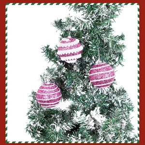 Close-up of pink glitter striped Christmas balls hanging on snowy tree branches