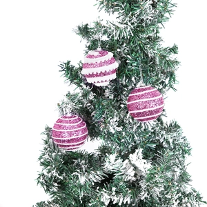 Pink and white striped Christmas balls with glitter finish hanging on a tree