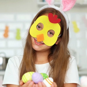 Kind mit gelber Osterküken-Filzmaske, Hasenohren und bunten Eiern in festlicher Szene