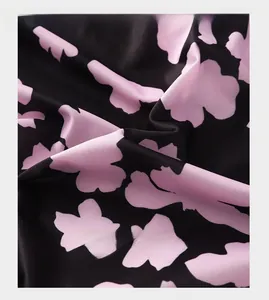 Close-up of smooth ice silk fabric with pink floral patterns on black background