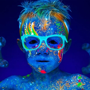 Close-up of vibrant UV fluorescent body paint and glowing glasses in dark party setting