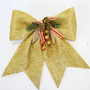 Detail of large gold sequin Christmas bow with natural pine cone and red berry ornaments