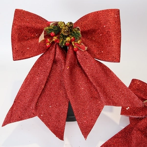 Detail of red glitter Christmas bow with natural pine cone and festive berry accents