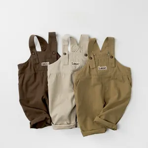 Detailed view of three cotton kids overalls with Luck embroidery and adjustable buttons