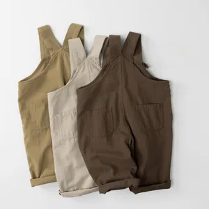 Flat lay detail showing cotton linen kids overalls in khaki, cream, and coffee brown colors