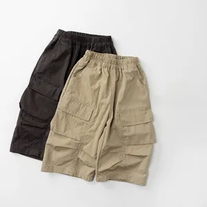 Detail view of elastic drawstring waist and cargo pockets on brown and khaki pants