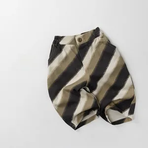 Close-up of kids striped loose pants with elastic waist, diagonal patterns and button detail