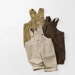 Detailed flat lay of children's cotton overalls in beige, mustard yellow and brown tones