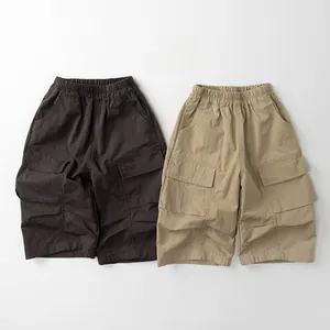 Detail of loose-fit cotton cargo shorts featuring elastic waist and large side flap pockets